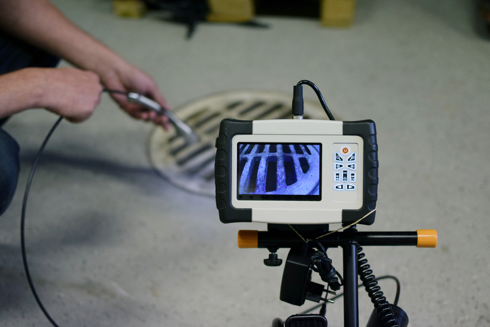 man using a specialized camera to view the sewer pipes