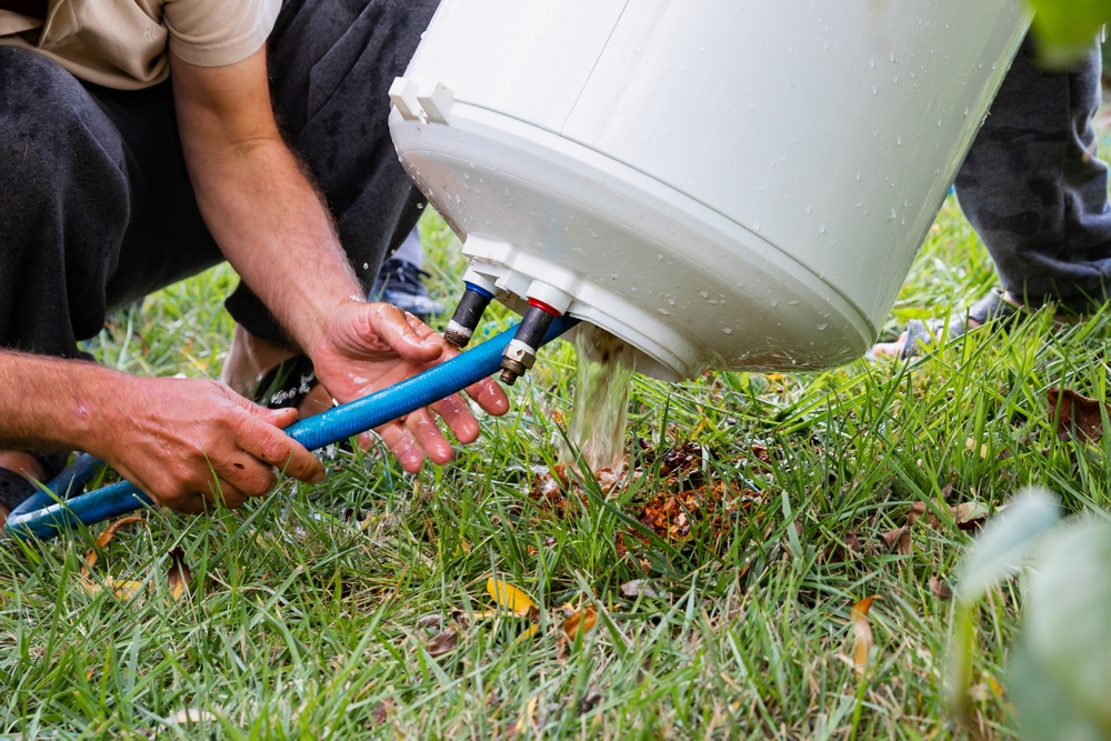 man flushing out water heater on grass