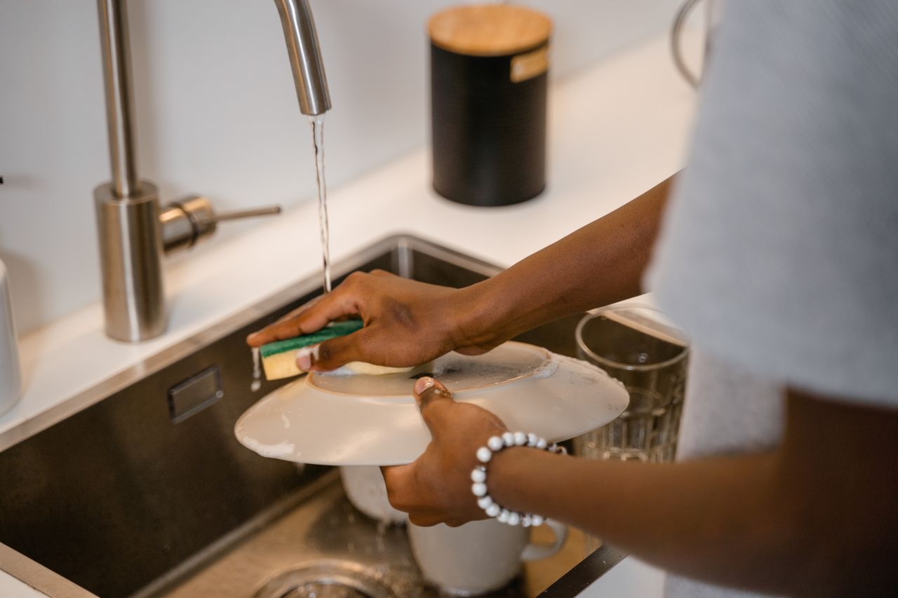 person washing dishes in sink